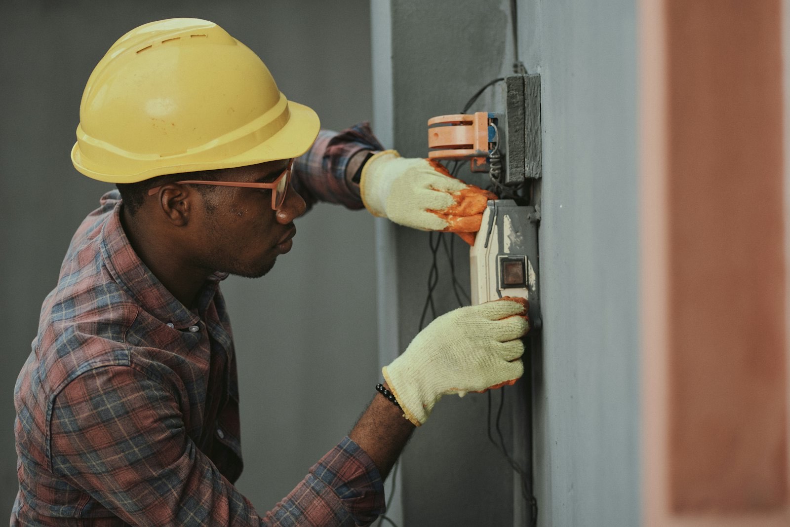 An electrician working on a panel with both hands busy